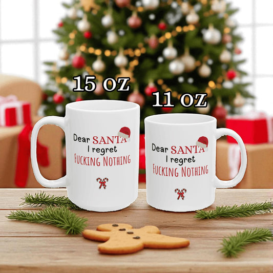 Two white mugs with humorous text in front of a Christmas tree and presents.