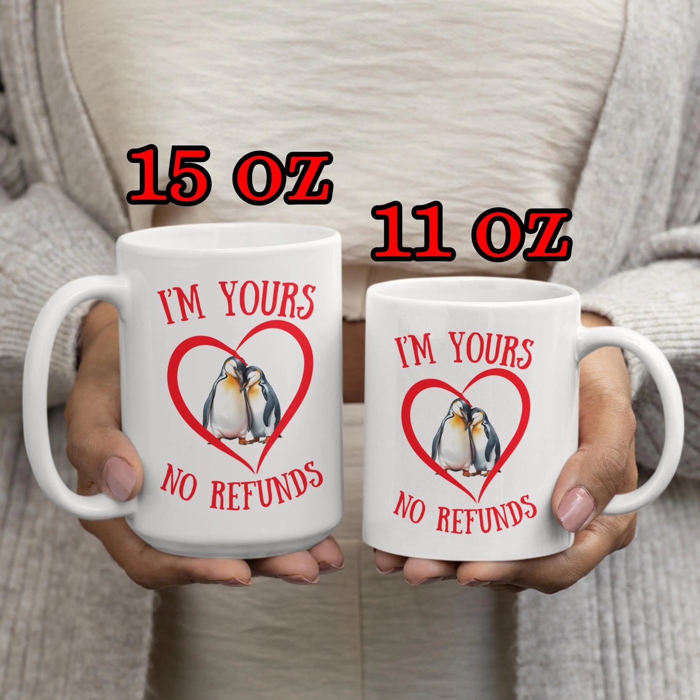 Two mugs with penguin design and text held by a person, labeled 15 oz and 11 oz.