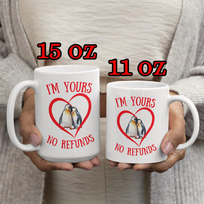 Two mugs with penguin design and text held by a person, labeled 15 oz and 11 oz.