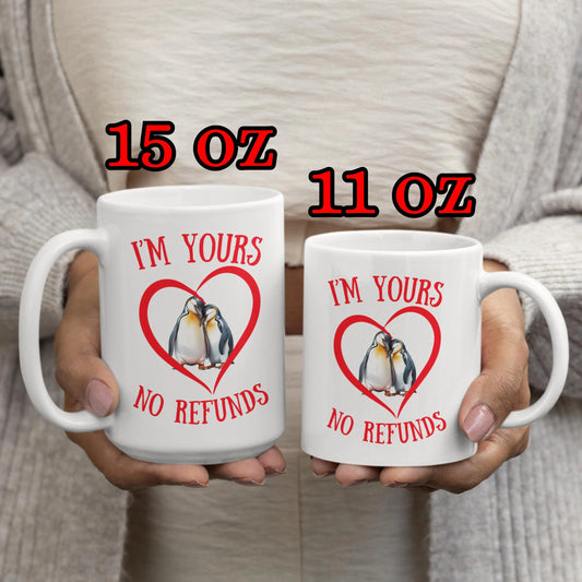 Two mugs with penguin design and text held by a person, labeled 15 oz and 11 oz.