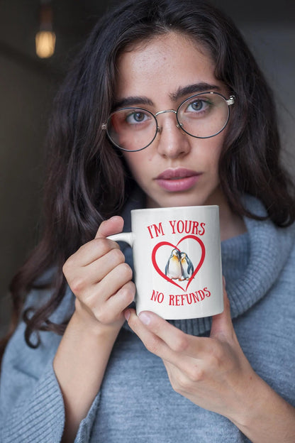 Woman holding a mug with a heart design and text, wearing glasses.