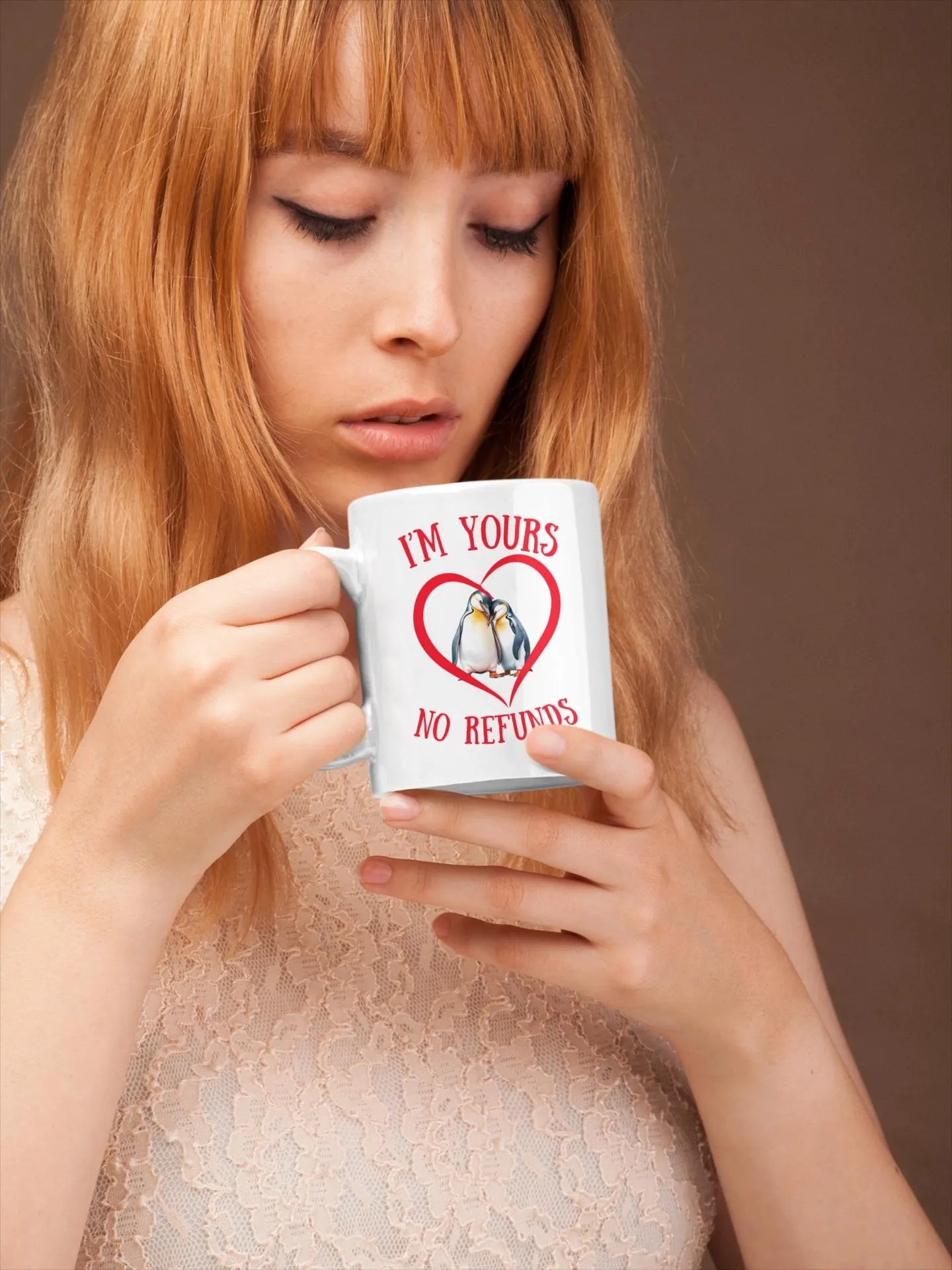 Woman holding a mug with a heart design and text, against a brown background