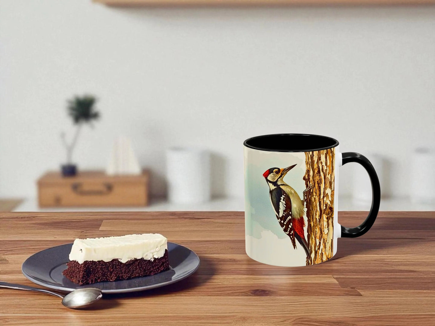 Mug with a bird design on a wooden table next to a slice of cake.
