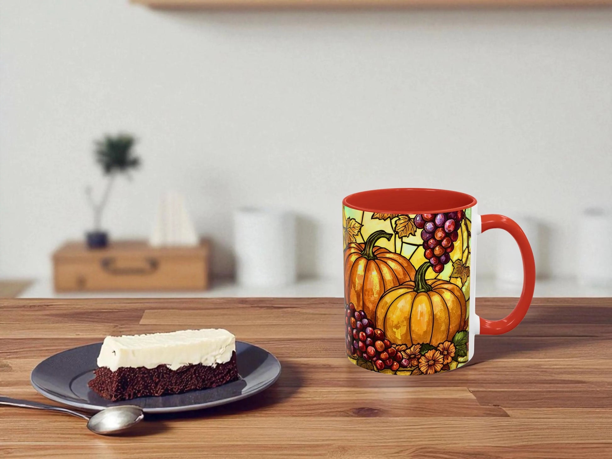 Decorative mug with pumpkins and grapes on a wooden table with a slice of cake.
