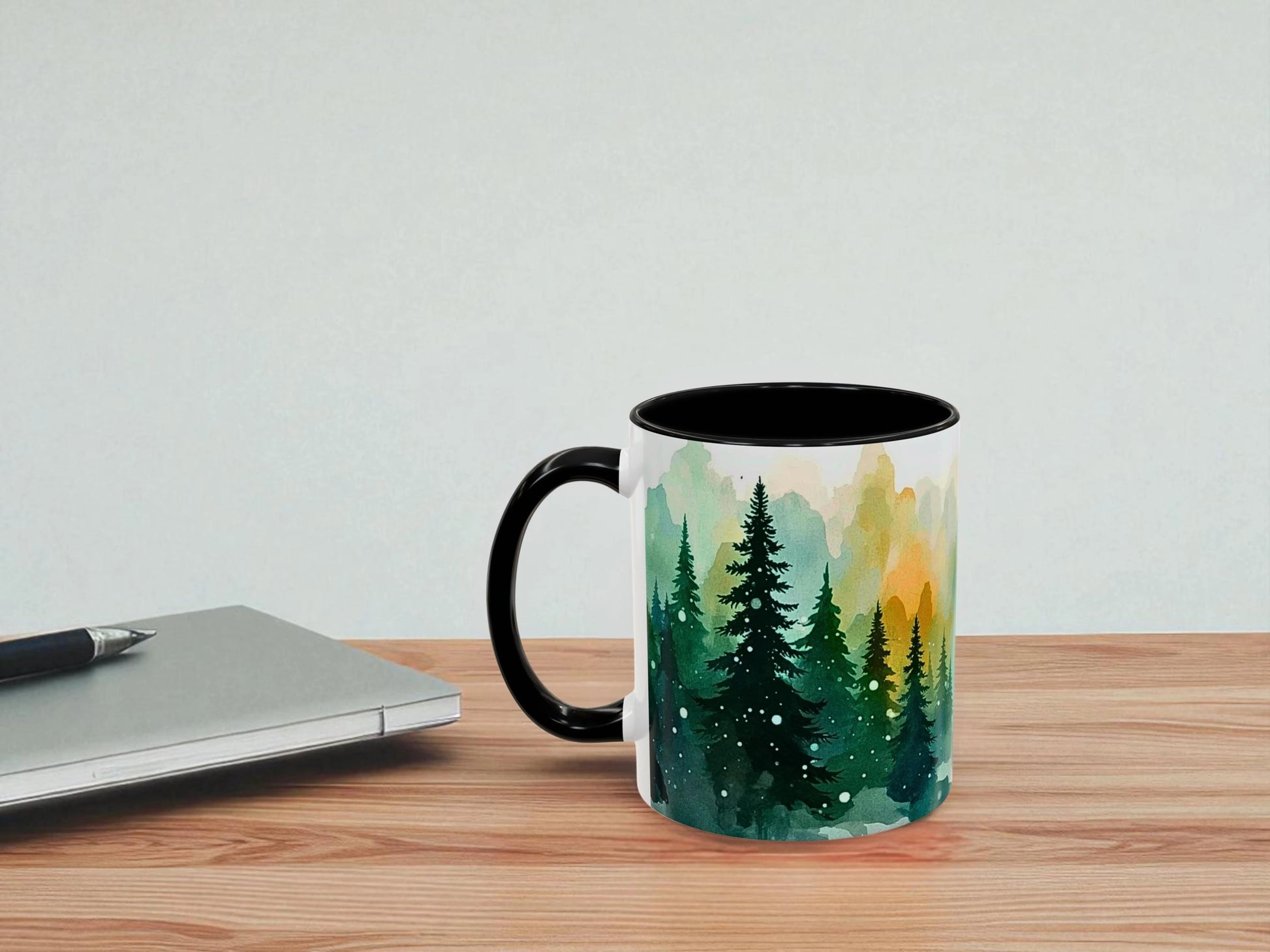Mug with nature design on a wooden table next to a laptop.