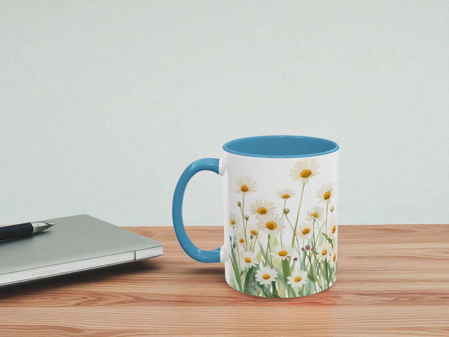 Mug with floral design on a wooden table next to a laptop.