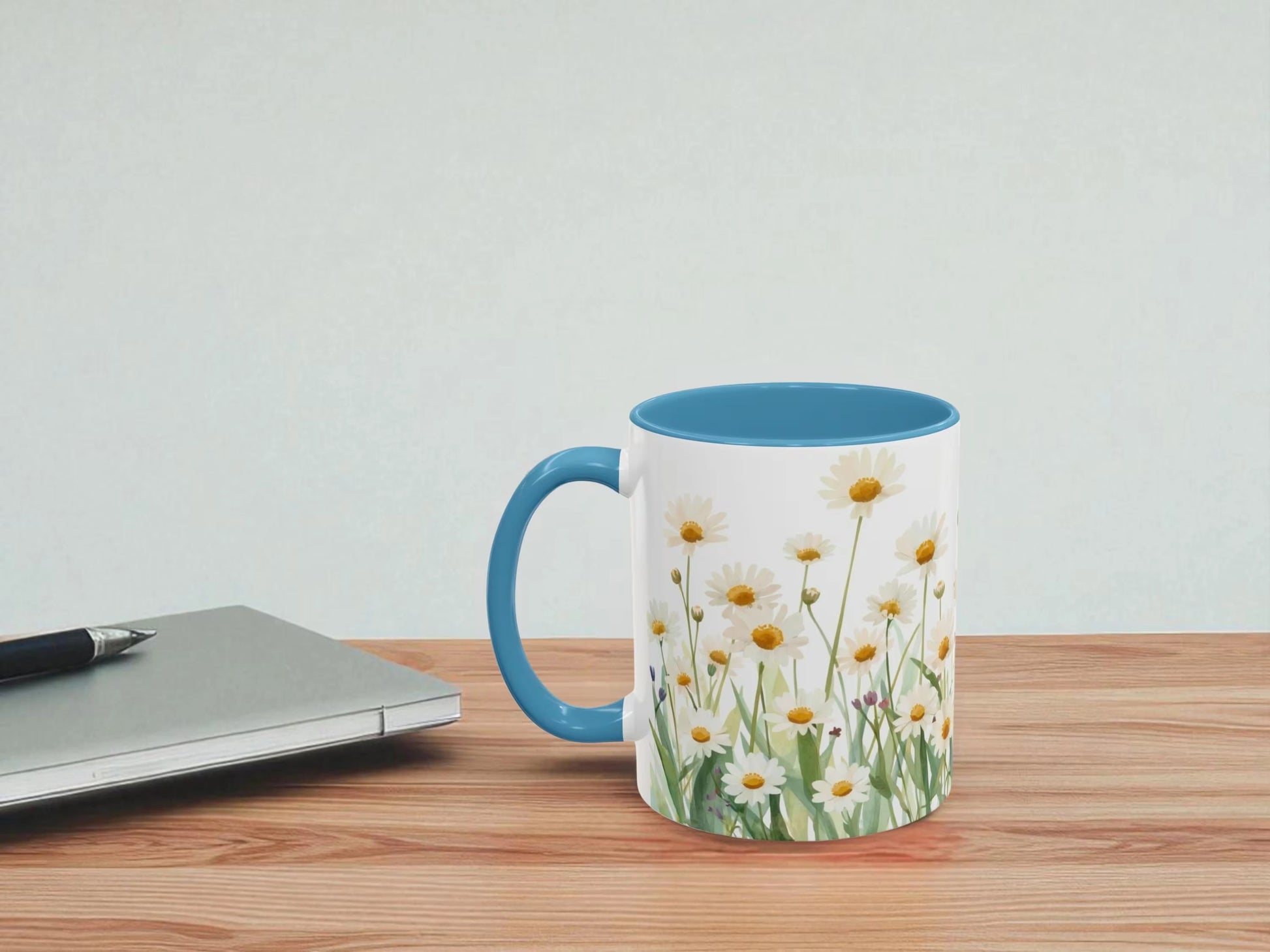 Mug with floral design on a wooden table next to a laptop.
