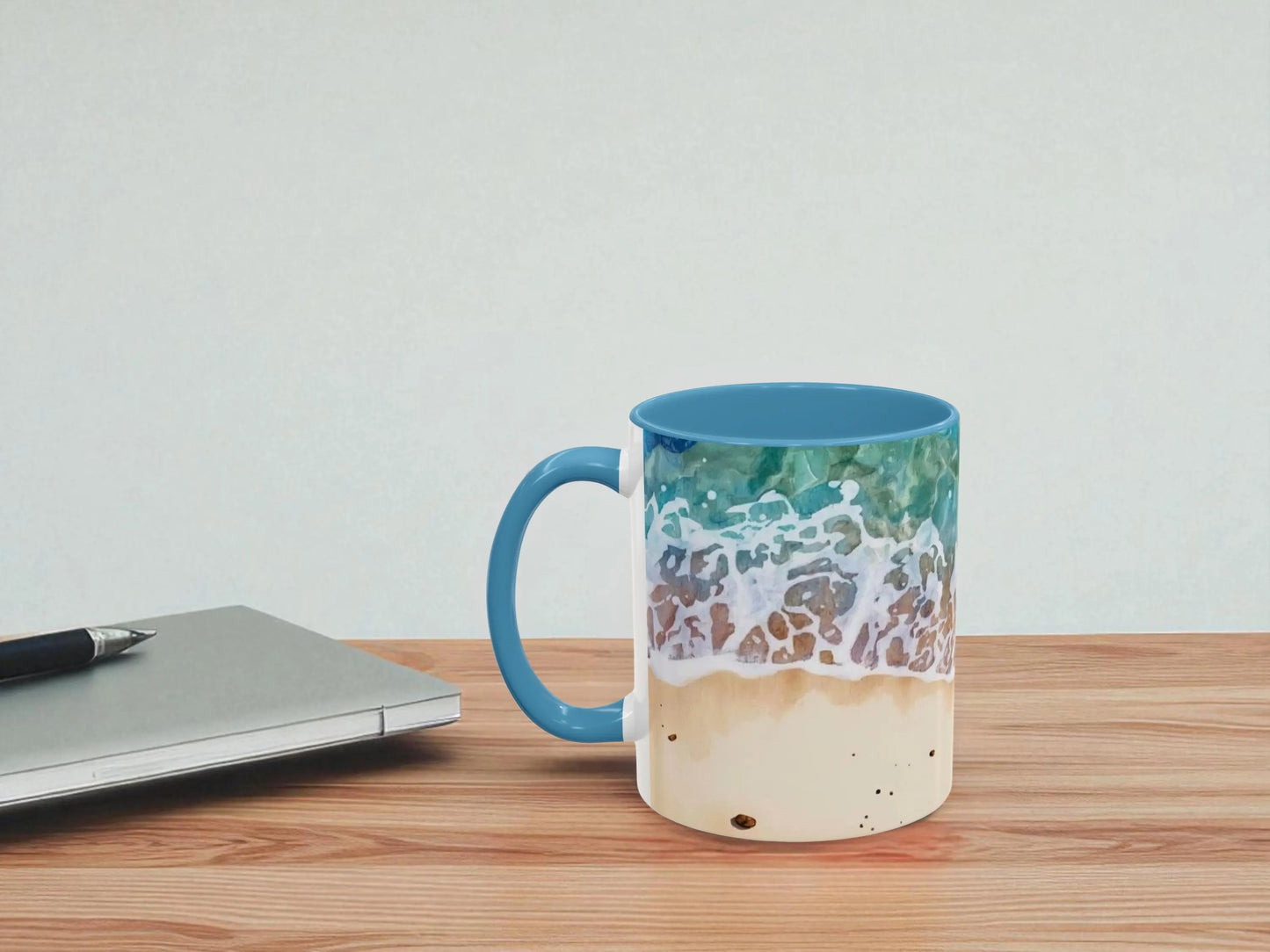 Mug with beach design on a wooden table next to a laptop