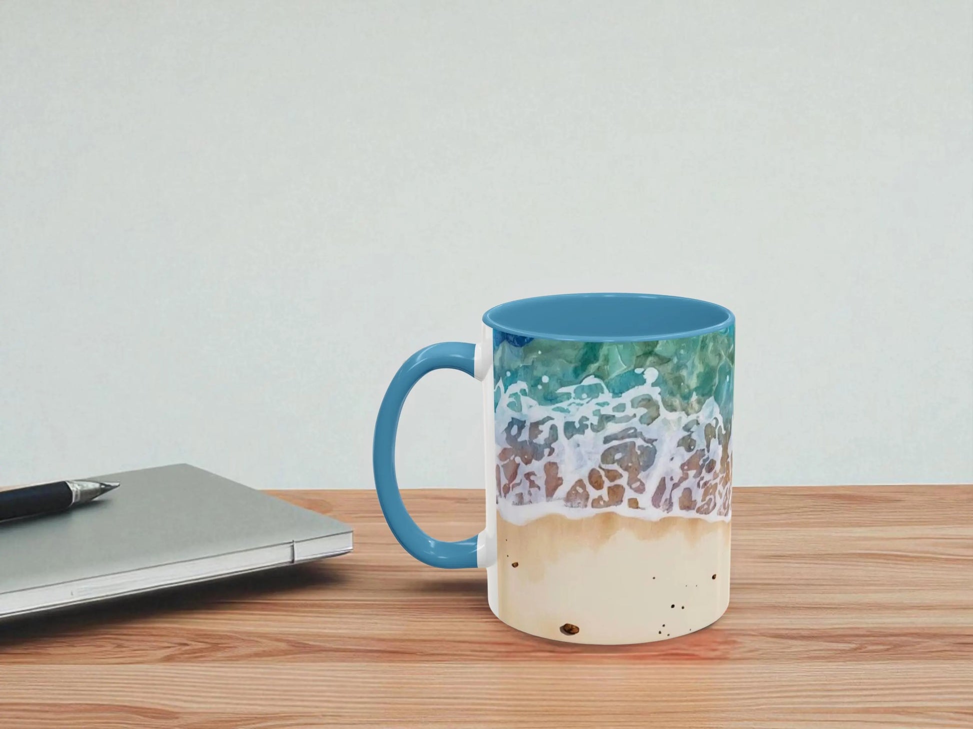 Mug with beach design on a wooden table next to a laptop