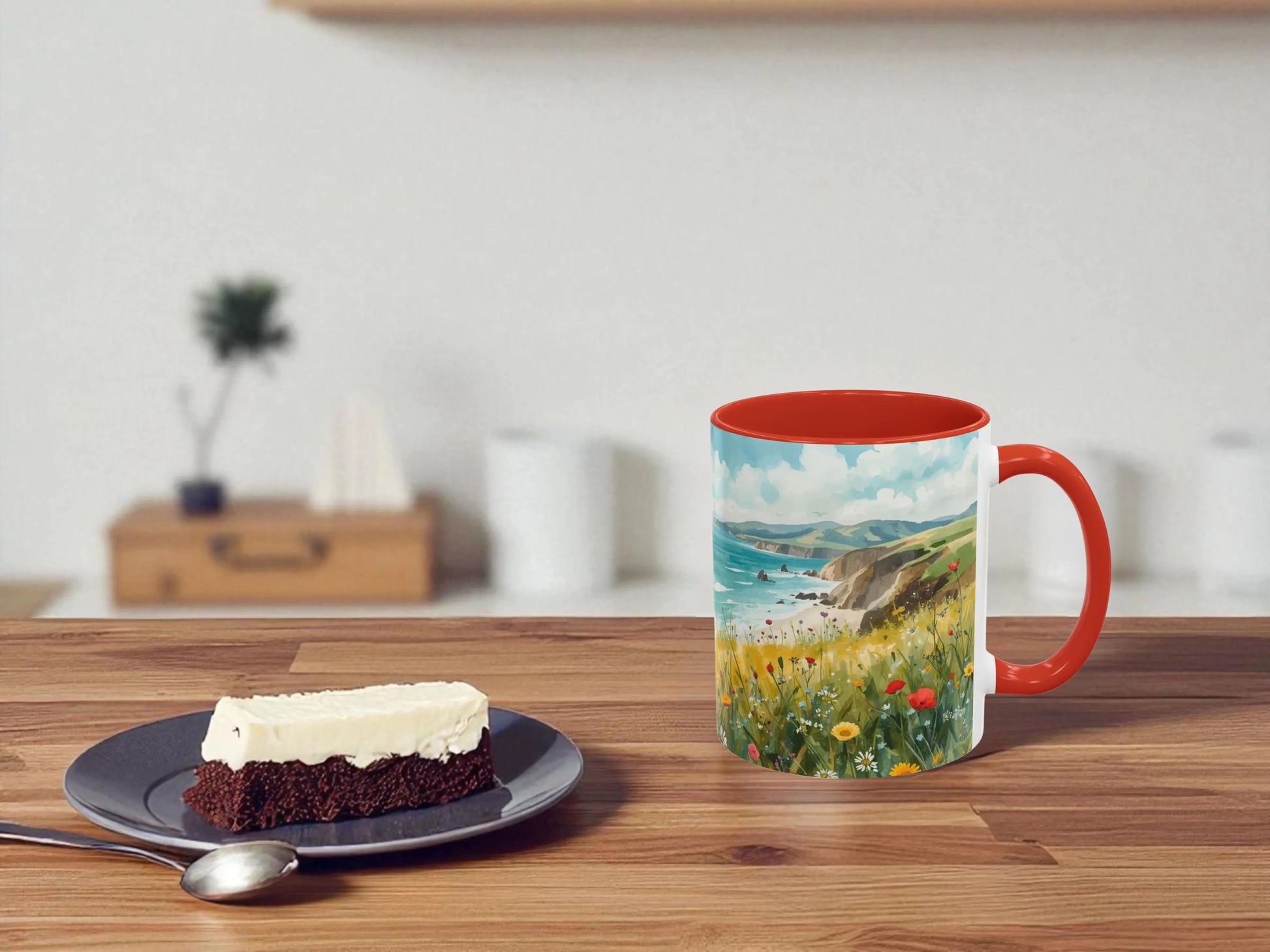 Mug with scenic design on a wooden table with a piece of cake.