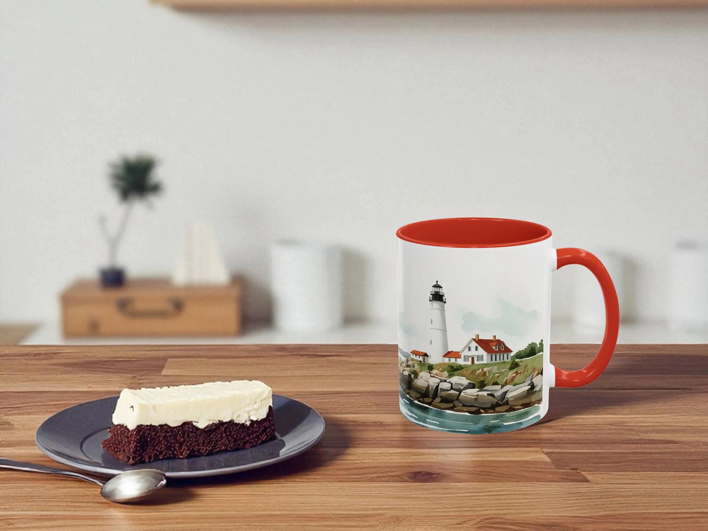 Mug with lighthouse design on a wooden table with a slice of cake.