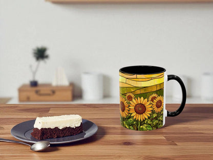 Mug with sunflower design on a wooden table with a piece of cake and spoon.