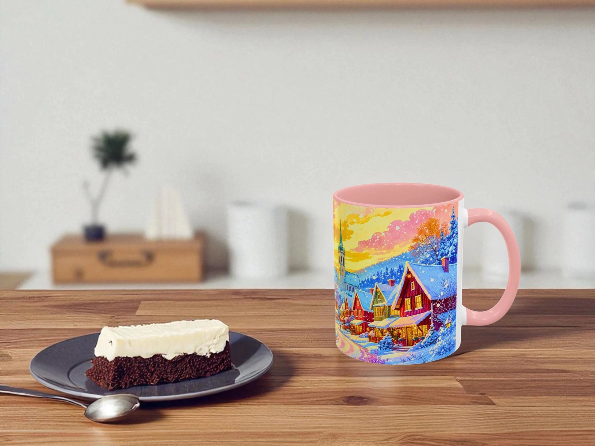 Colorful mug with a scenic design on a wooden table next to a slice of cake.