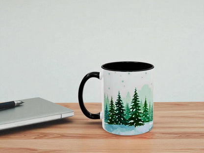 Mug with forest design on a wooden table next to a laptop.