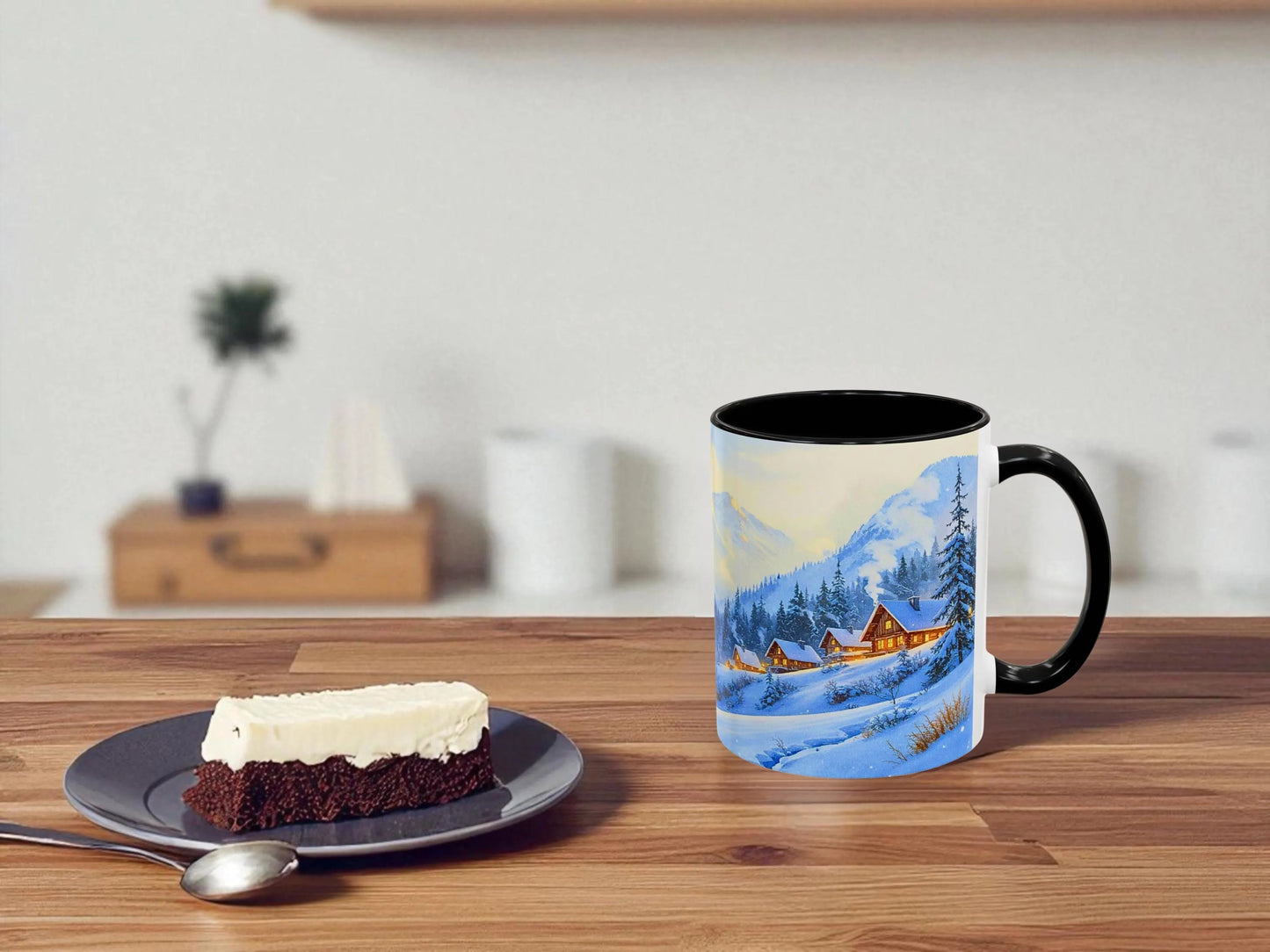 Mug with a scenic design on a wooden table next to a slice of cake.