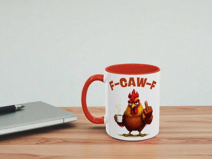 Mug with a rooster design and 'F-CAW-F' text on a wooden table with a laptop.