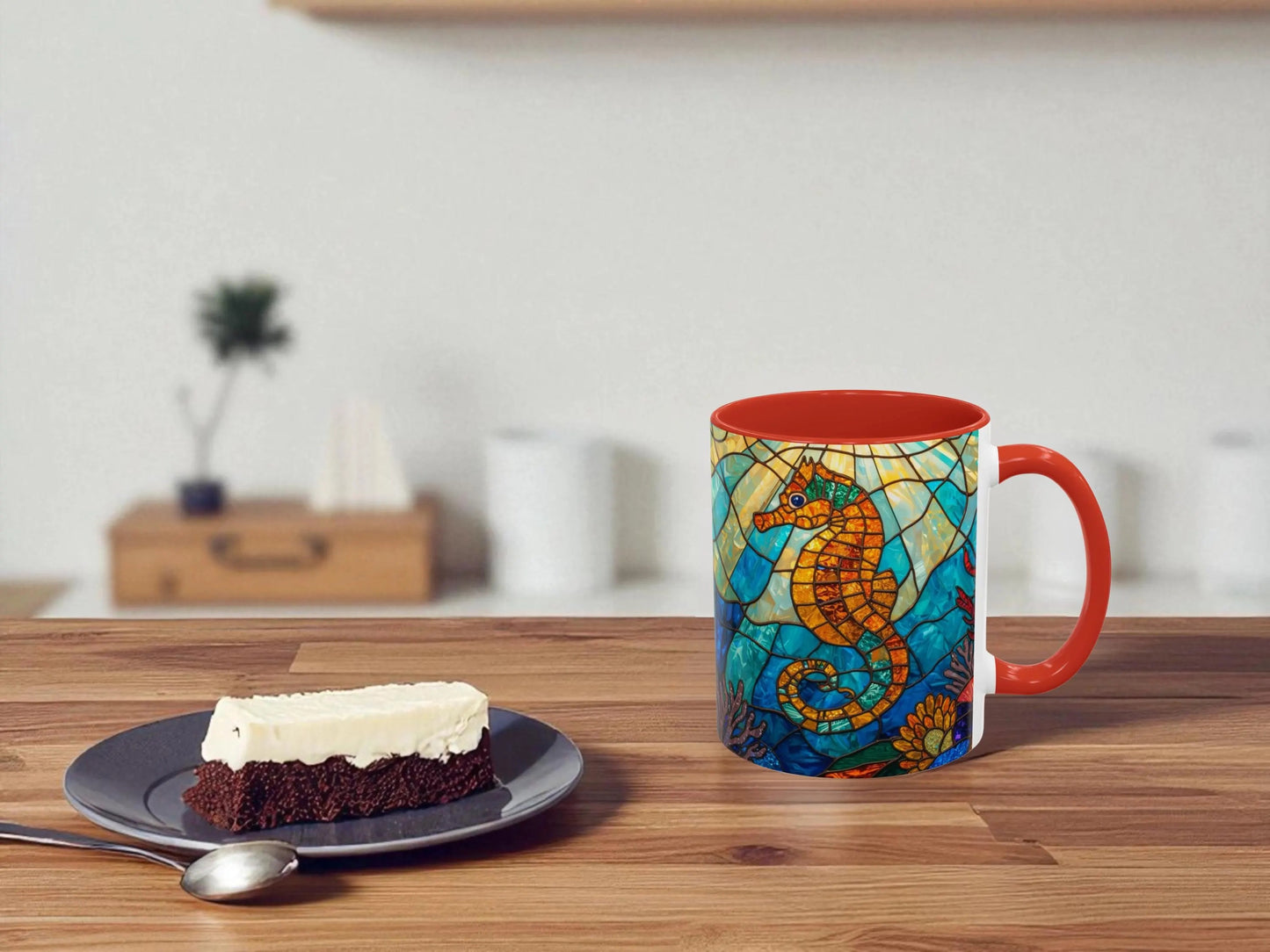 Colorful mug with a seahorse design on a wooden table next to a slice of cake.