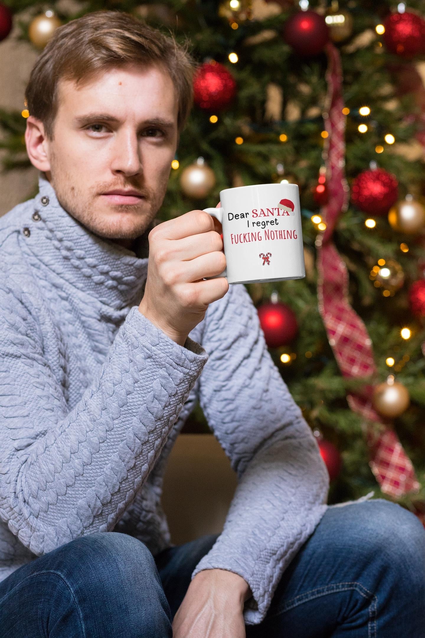 Man holding a mug with text in front of a decorated Christmas tree