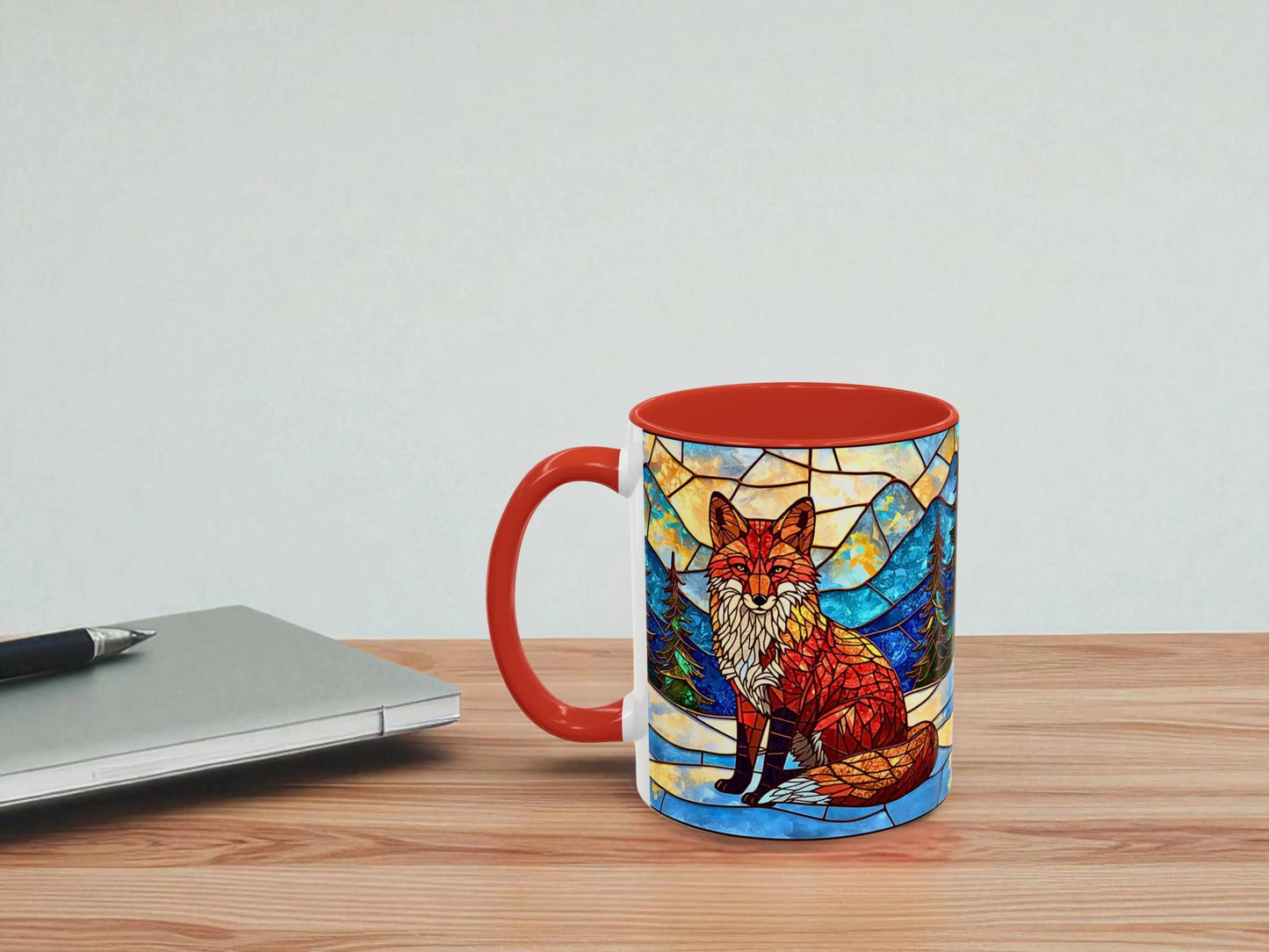 Mug with fox design on a wooden table next to a laptop.