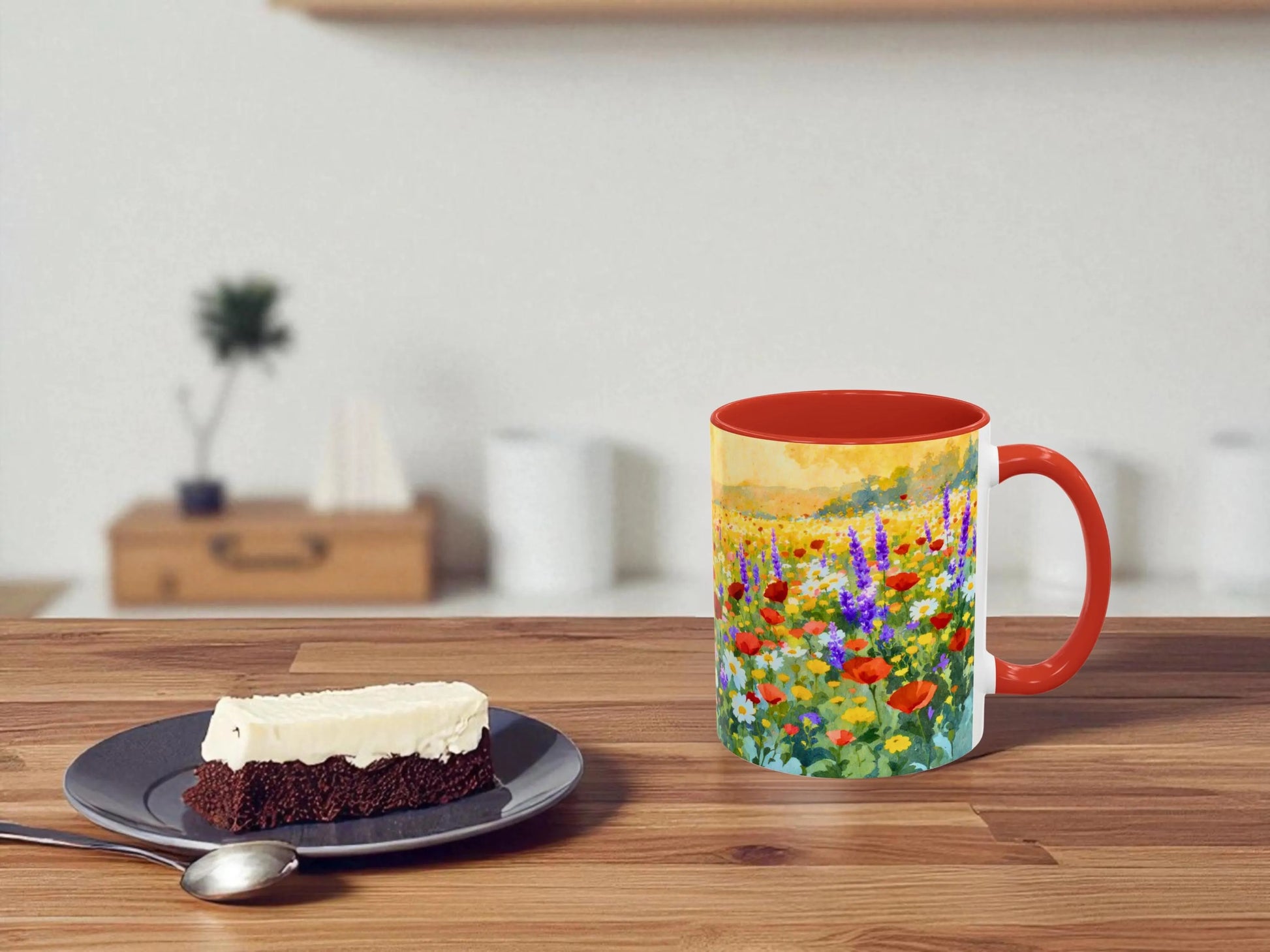 Mug with floral design on a wooden table with a slice of cake and spoon.