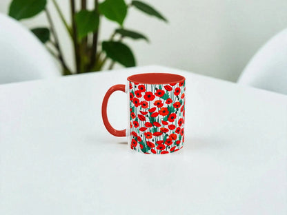 Mug with red floral pattern on a white surface with a plant in the background