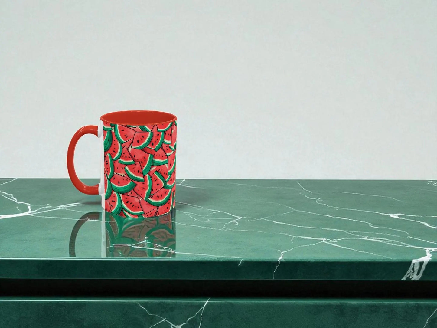 Red mug with watermelon pattern on a green marble surface
