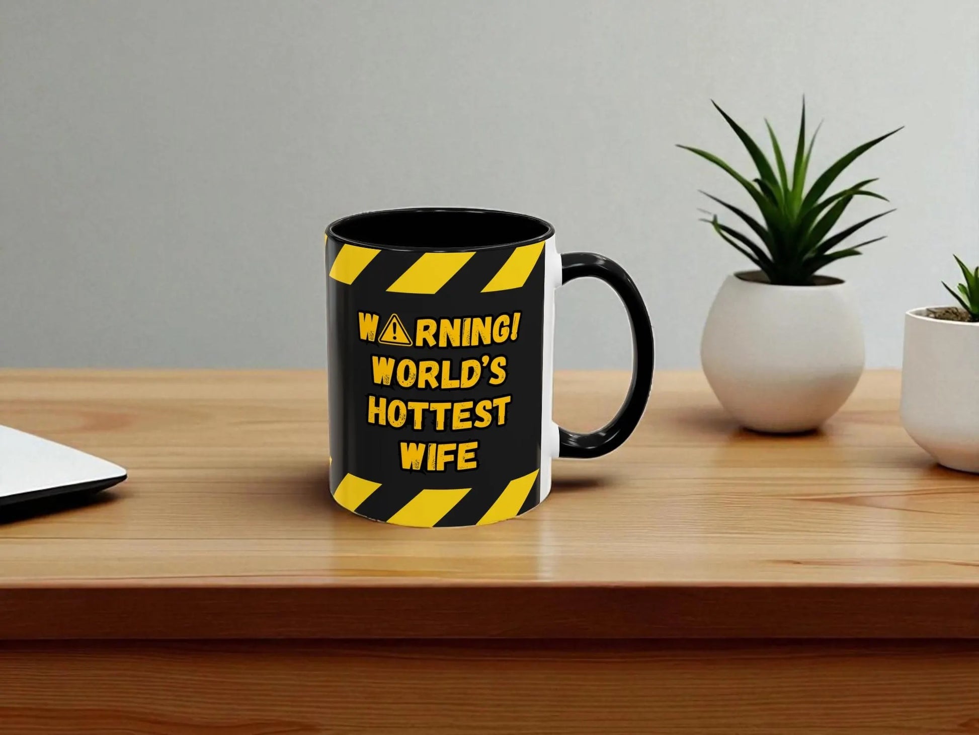 Mug with 'Warning! World's Hottest Wife' text on a wooden table with plants.