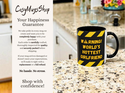 Mug with 'Warning! World's Hottest Girlfriend' text on a kitchen counter, with 'CosyMugsShop' branding.
