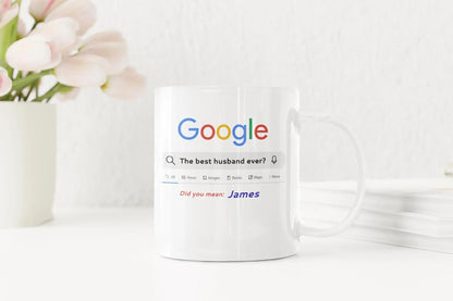 White mug with Google search query printed on it, next to a vase of flowers.