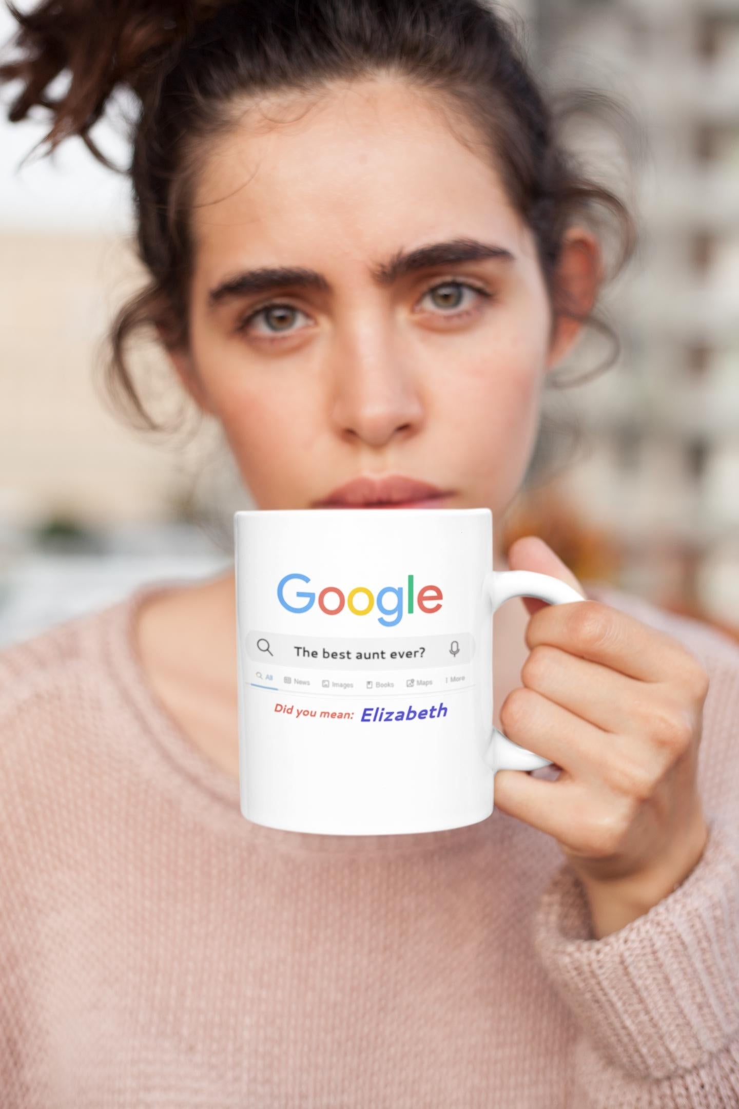 Person holding a mug with a Google search bar, blurred background