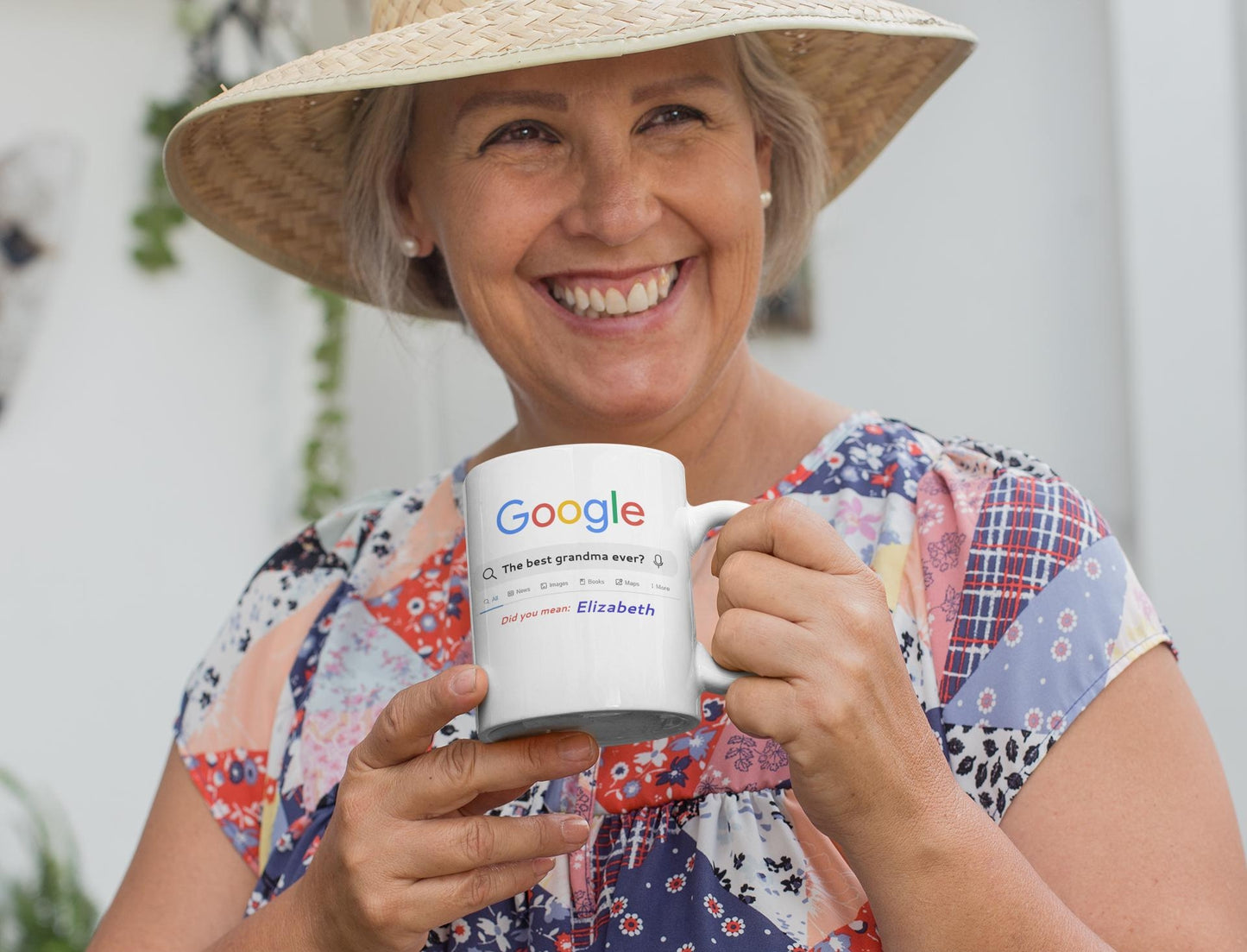 Woman holding a mug with 'Google' printed on it, wearing a straw hat and floral dress.