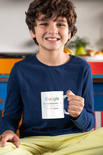 Child holding a mug with a colorful design, sitting in a kitchen.