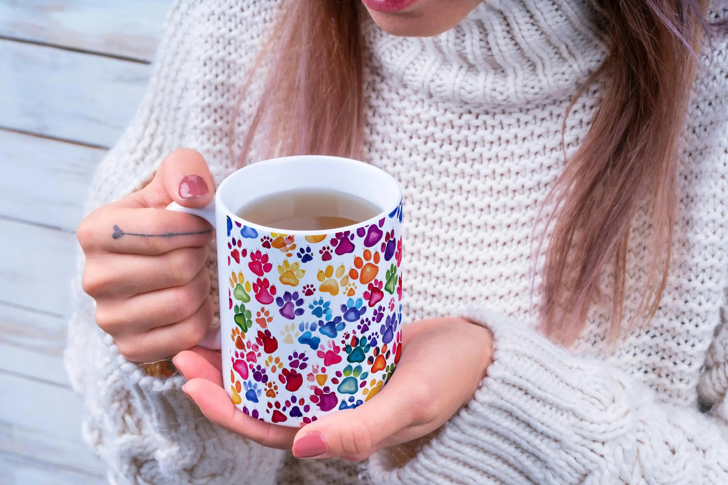 Person holding a mug with colorful paw print design