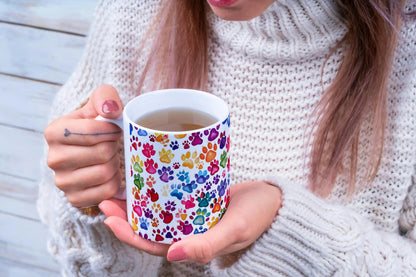 Person holding a mug with colorful paw print design
