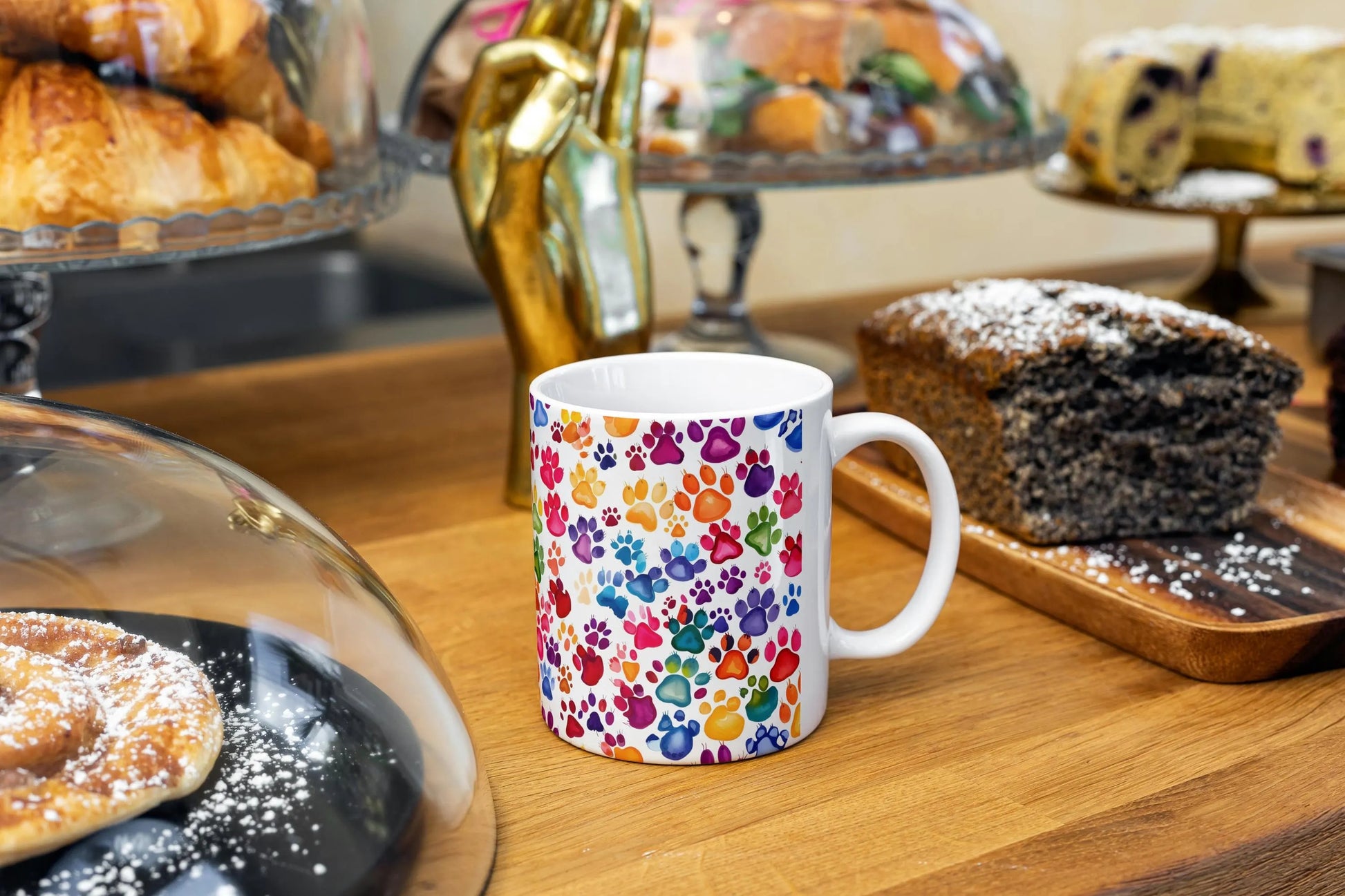 Colorful mug with paw prints on a wooden table with pastries in the background