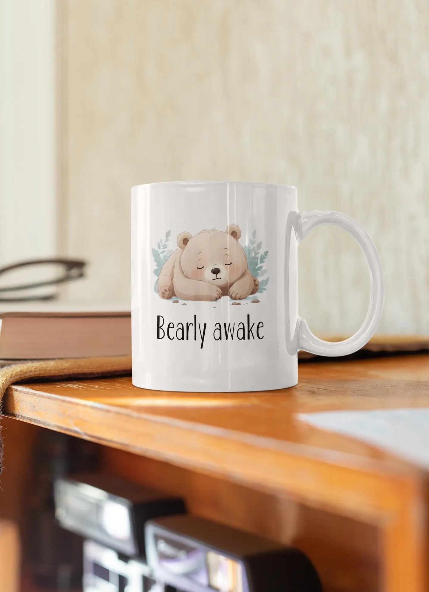 White mug with a bear illustration and 'Bearly awake' text on a wooden surface.